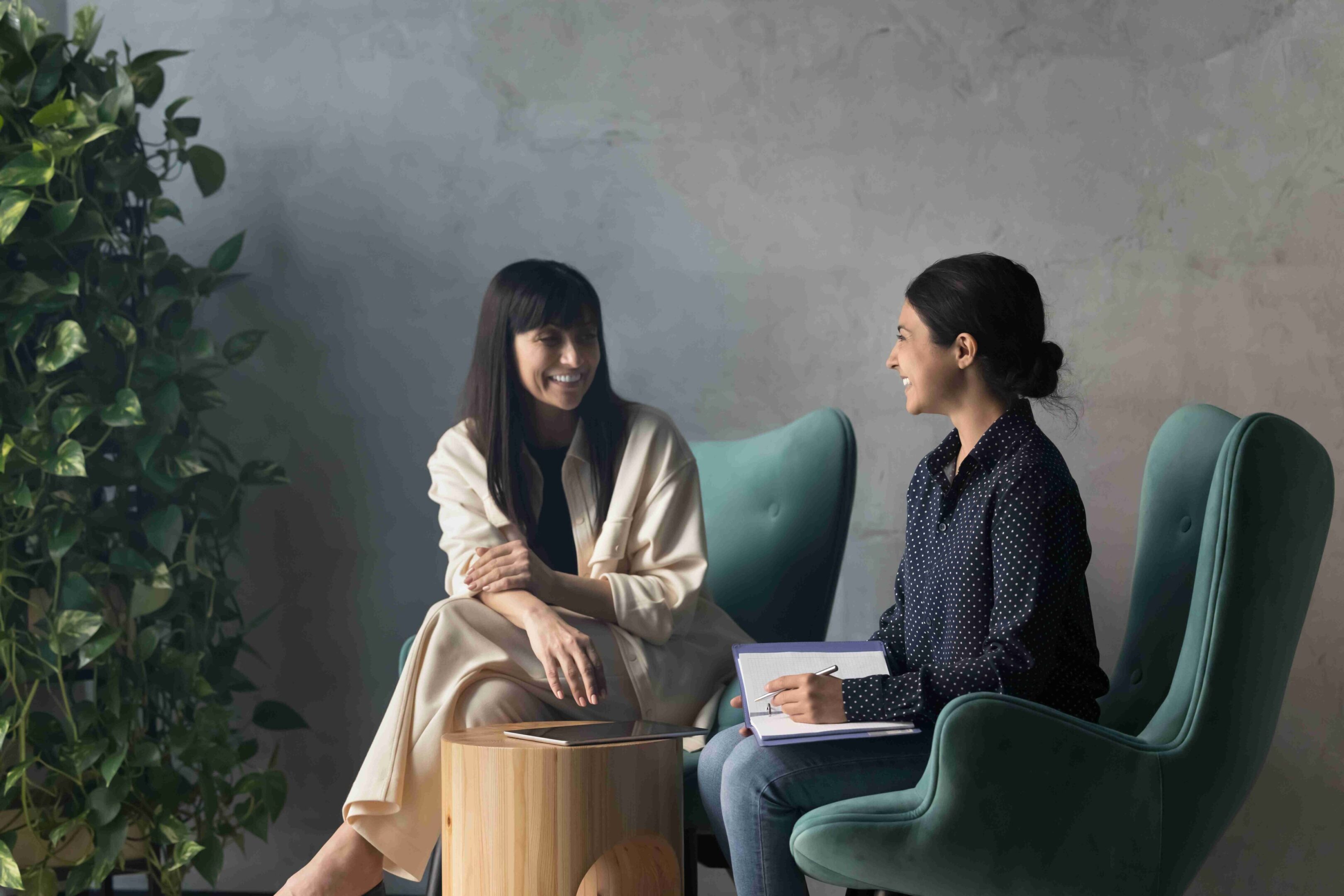 Two women engaged in a friendly conversation in a modern, cozy room.
