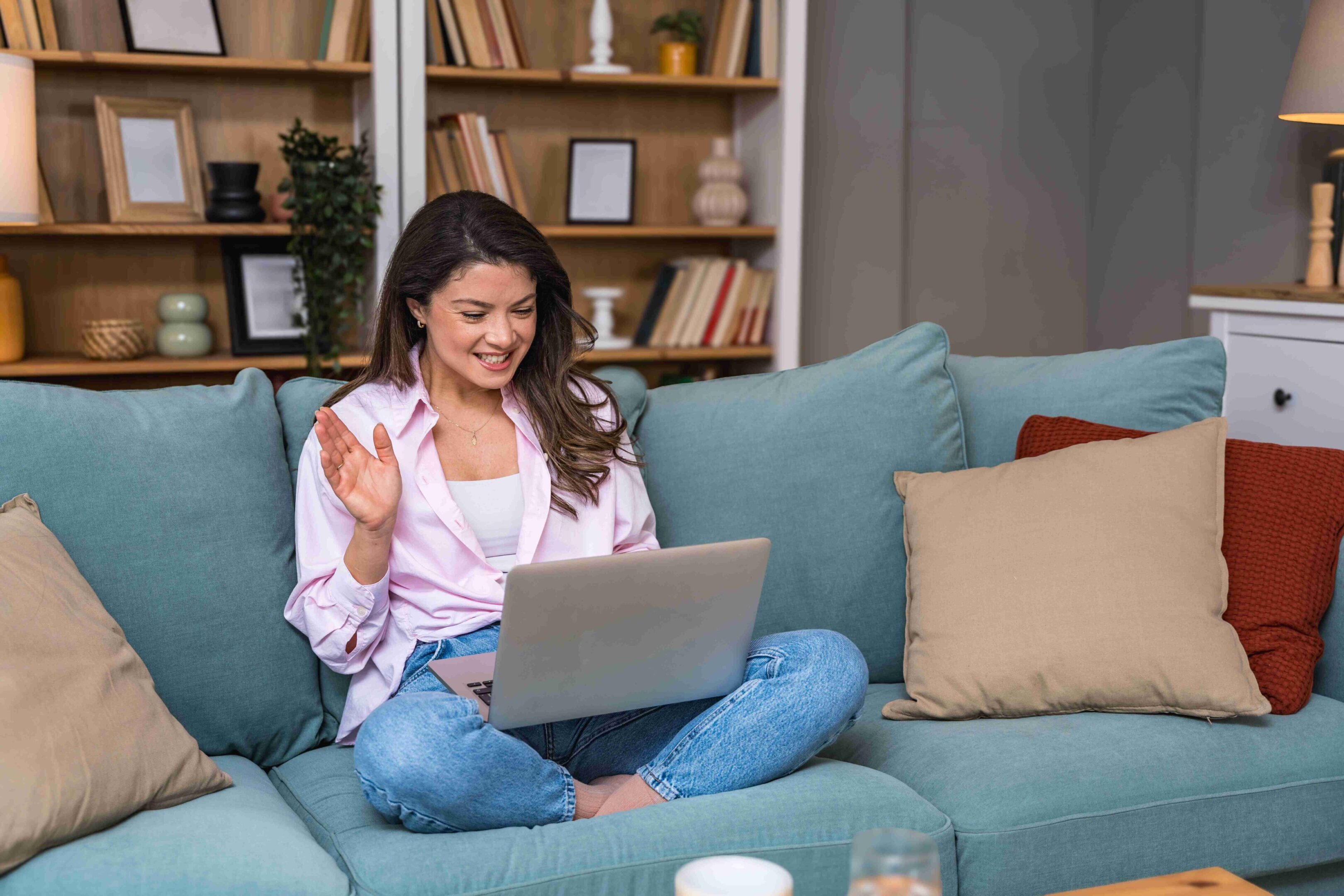 Young woman happily using laptop on a cozy sofa.