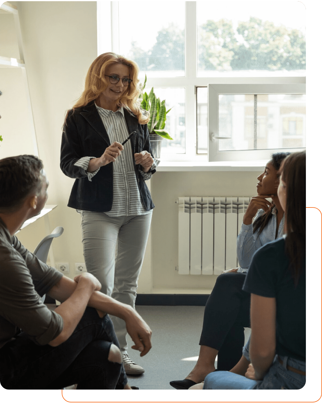 A woman presents to a small group in a bright room.