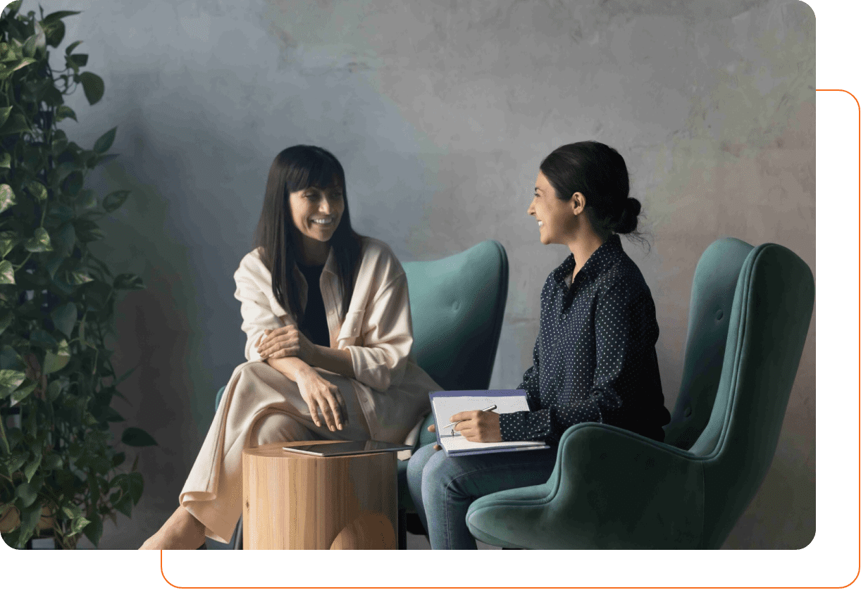 Two women engaged in a friendly conversation while seated comfortably.