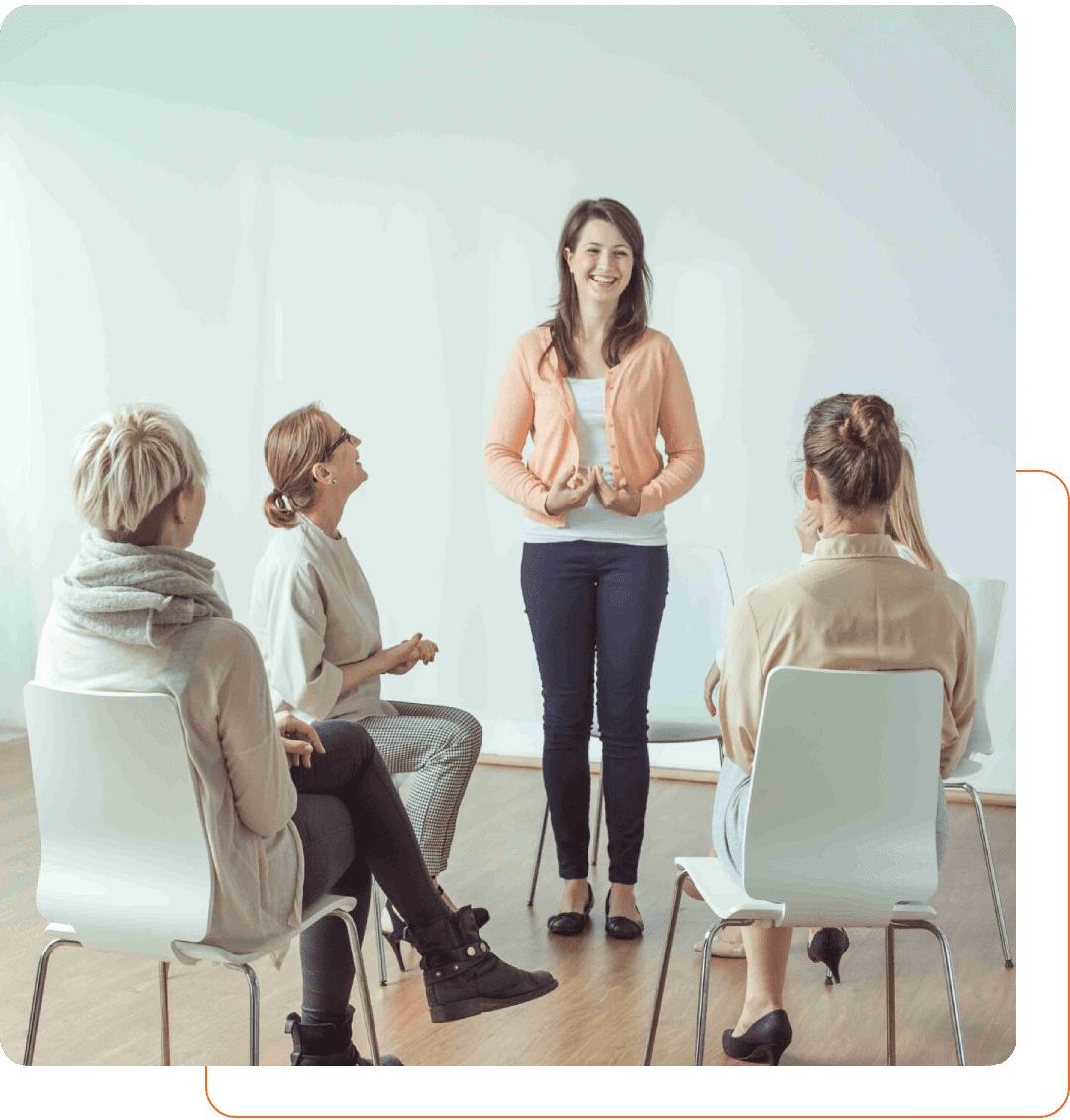A woman leading a discussion with three seated participants in a bright room.
