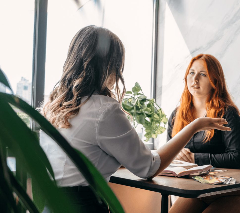 Two women engaged in a serious conversation at a table.