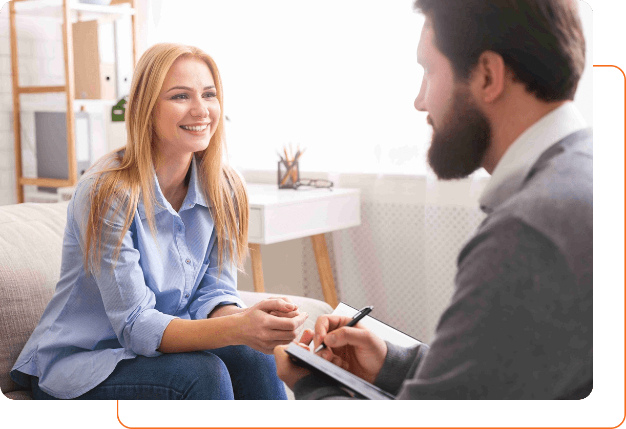 A woman smiling while talking to a therapist in a bright office.